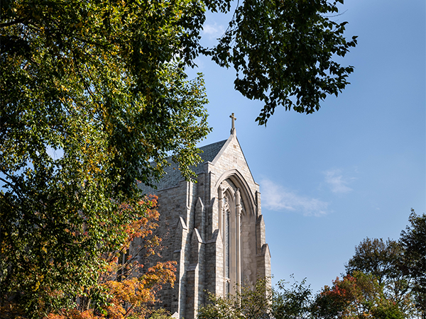 Egner Memorial Chapel is seen against a blue sky with leafy trees in the foreground.